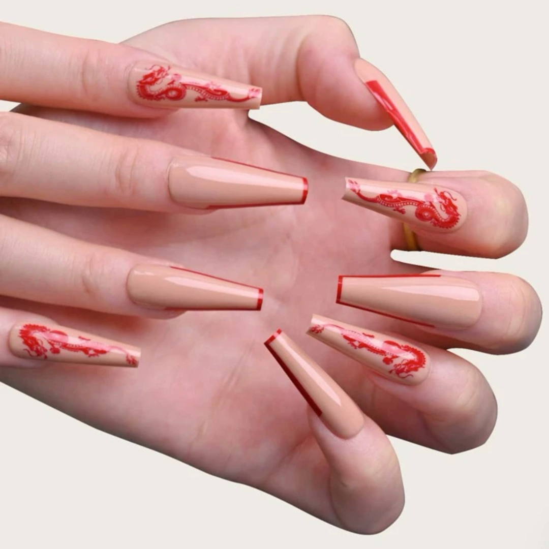 false press on nails that are a very light brown colour with a red outline and a dragon design on the accent nails in a long coffin shape 