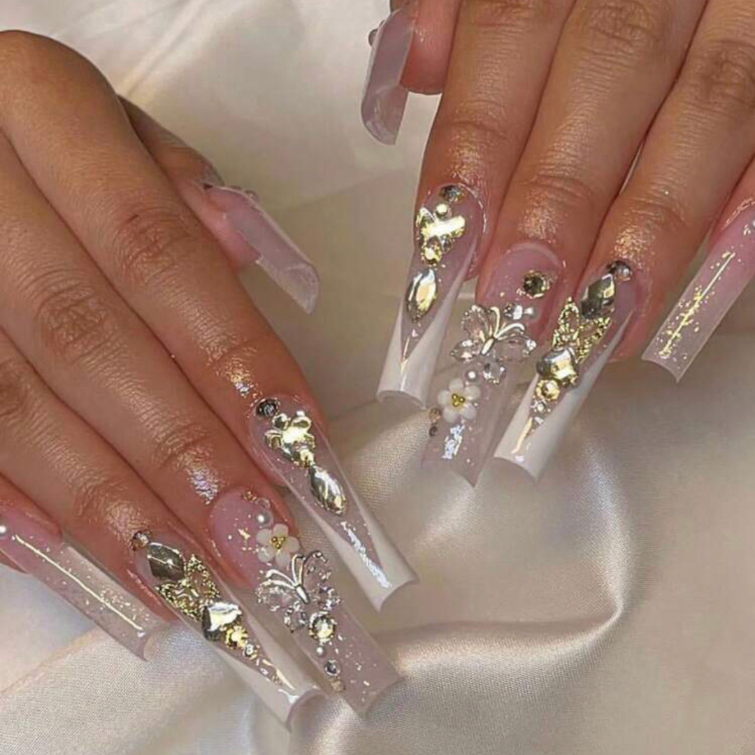 long press on nails that are shaped square and have big butterfly gems on the accent nails and a white ombre french tip effect on the other nails