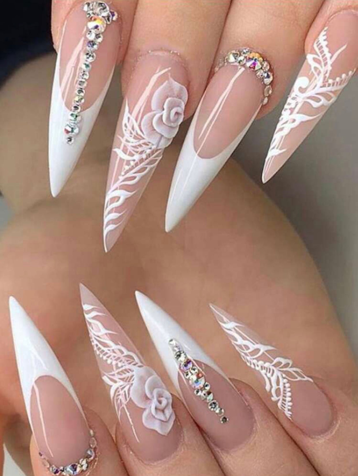 false press on nails in a stiletto shape with jewels and airbrush flower designs on the accent nails